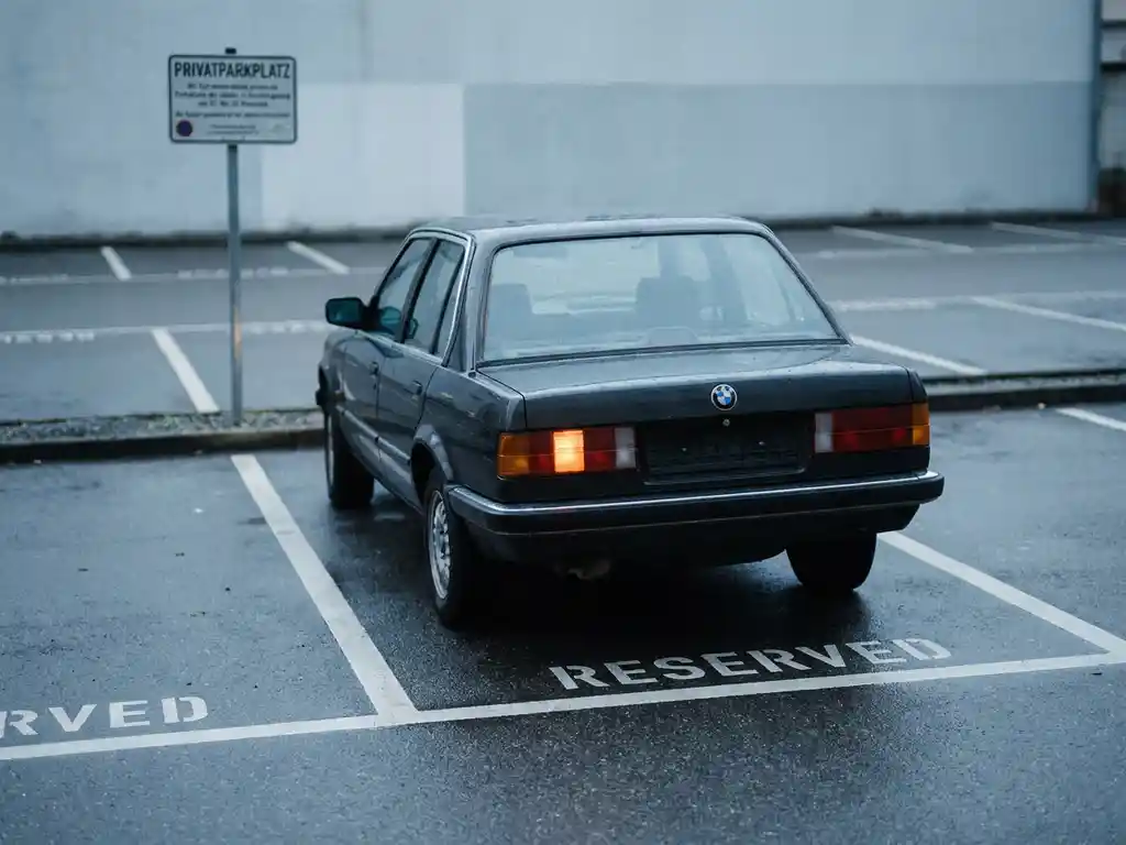 Auto parkt unberechtigt auf einem Privatparkplatz mit verschwommenem Privatparkplatz-Schild im Hintergrund.